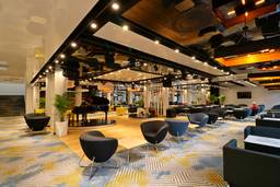 Stilvolle Lobby mit modernen Sesseln, Klavier und buntem Bodendesign